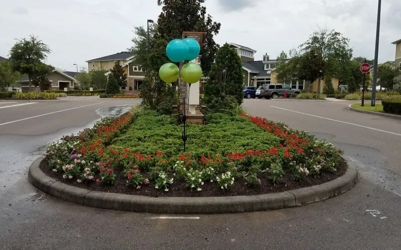 Landscaped median with flowers and balloons in a residential street.